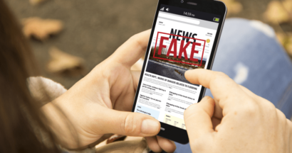 Man holding mobile phone with Fake News headline