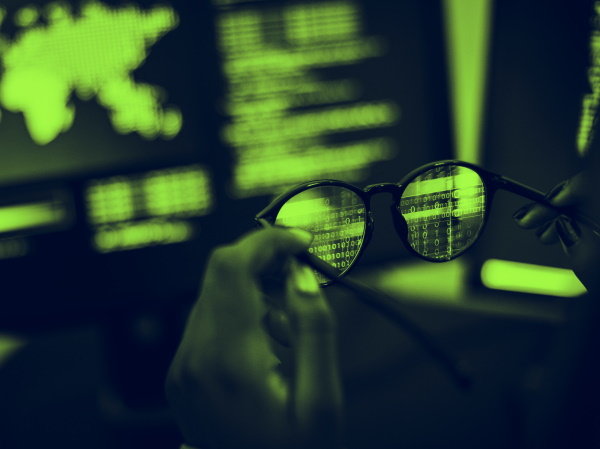 Image shows someone holding a pair of glasses up to a computer screen displaying code. Are coded testing tools as cheap as they seem?