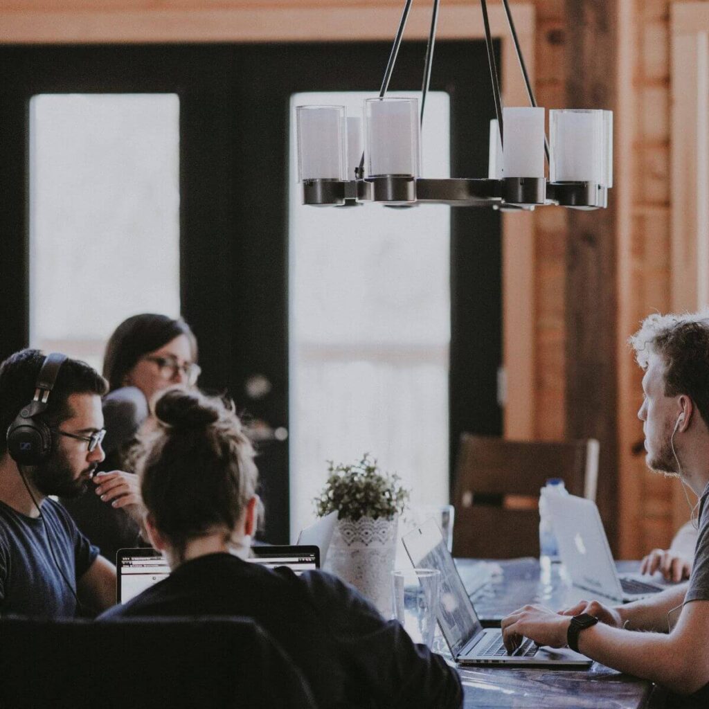 4 people working at a table with laptops