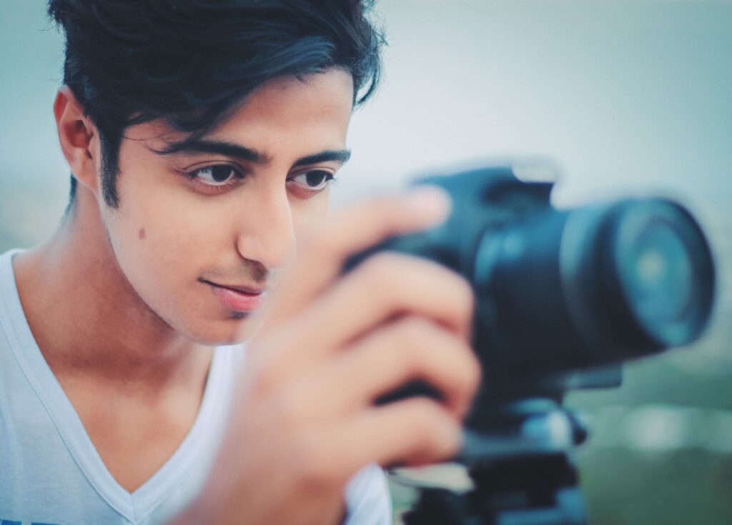 A man with dark hair holds up a camera